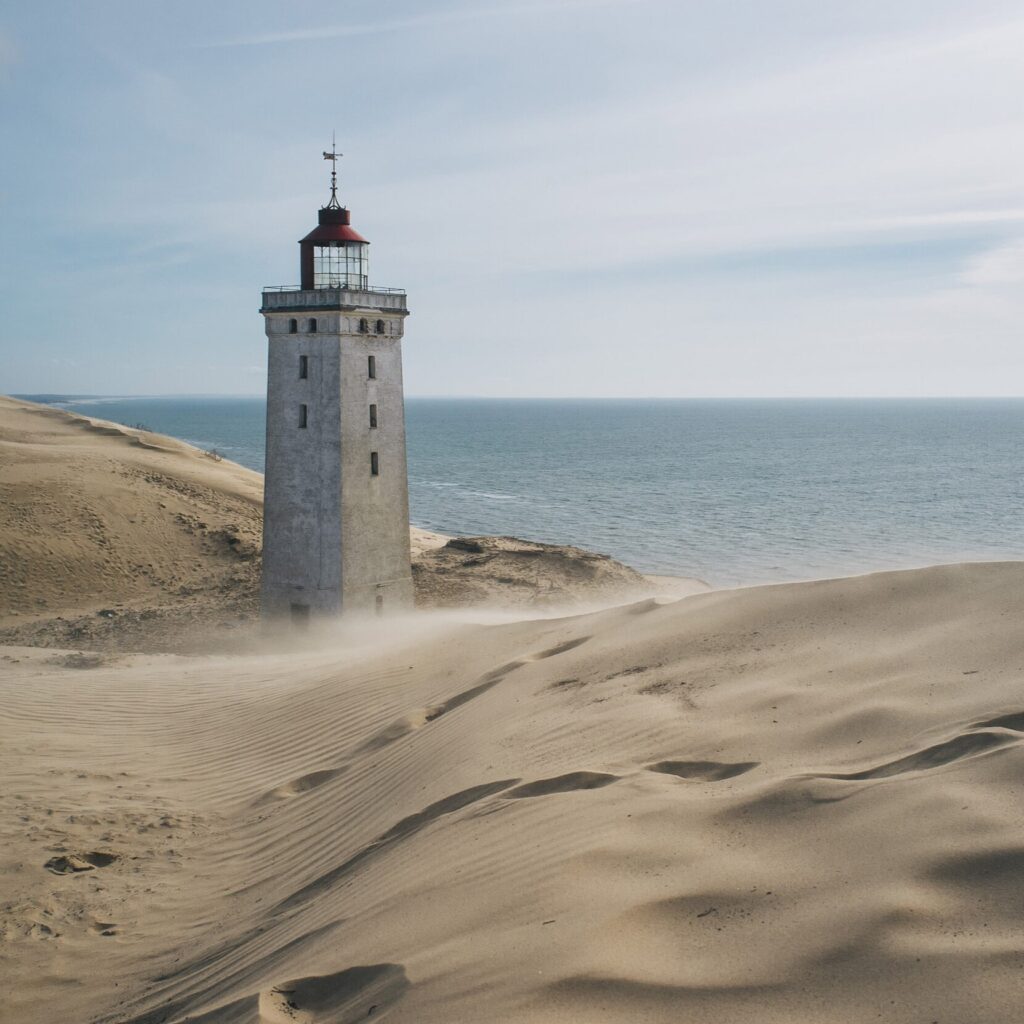 a lighthouse is being rolled over by a sand dune