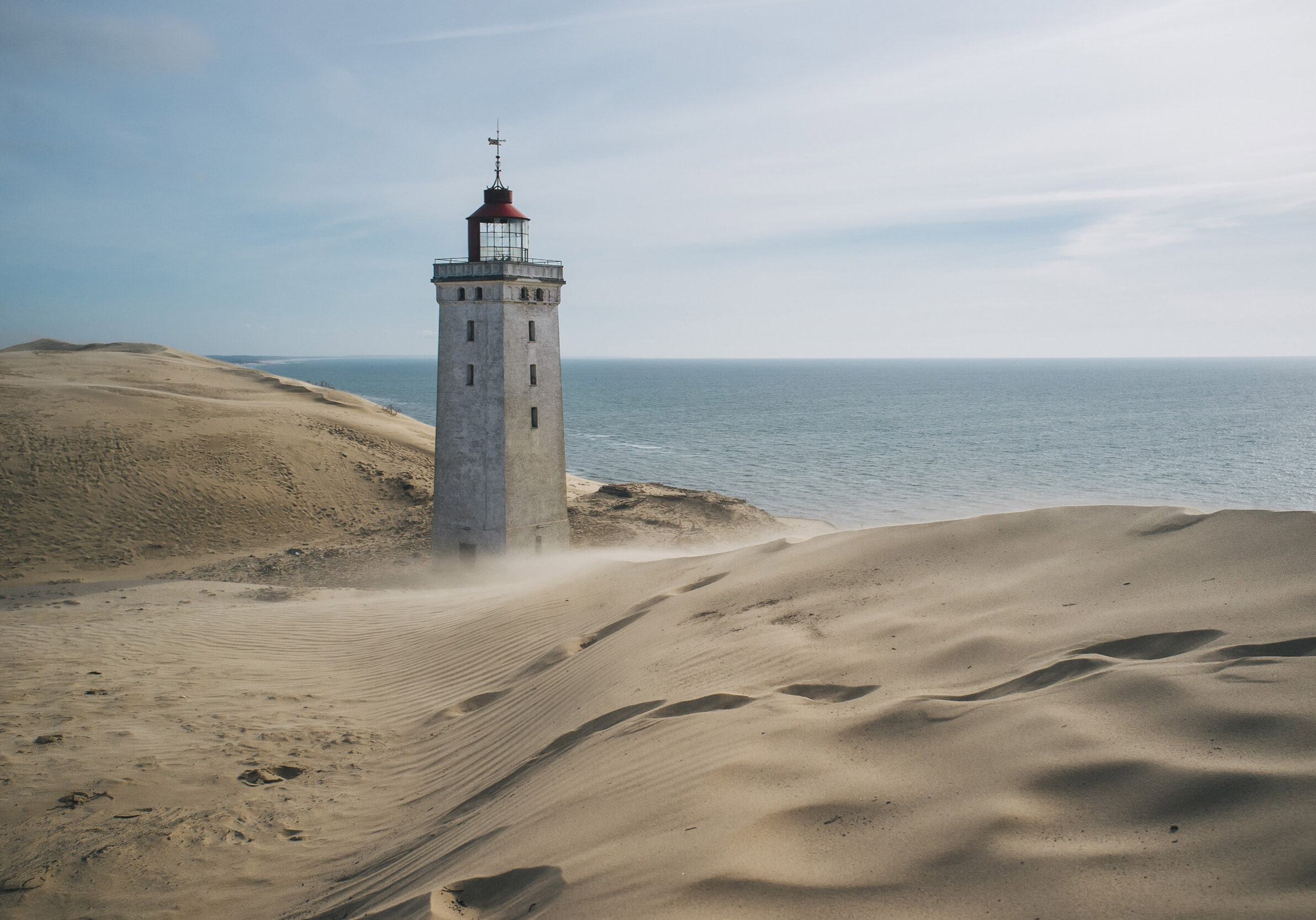 a lighthouse is being rolled over by a sand dune